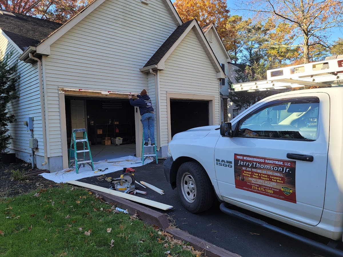 Jerry Thomson Jr. working on a garage door beside his branded Your Neighborhood Handyman work truck